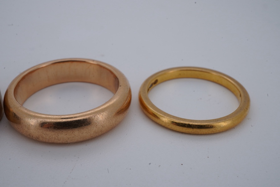 Four gold rings, comprising: a 22ct gold wedding band, size M, British assay marks, gross weight 3 grams; a 9ct gold band with a panelled finish, size N, British hallmarks, gross weight approximately 3.5 grams; a bicolou
